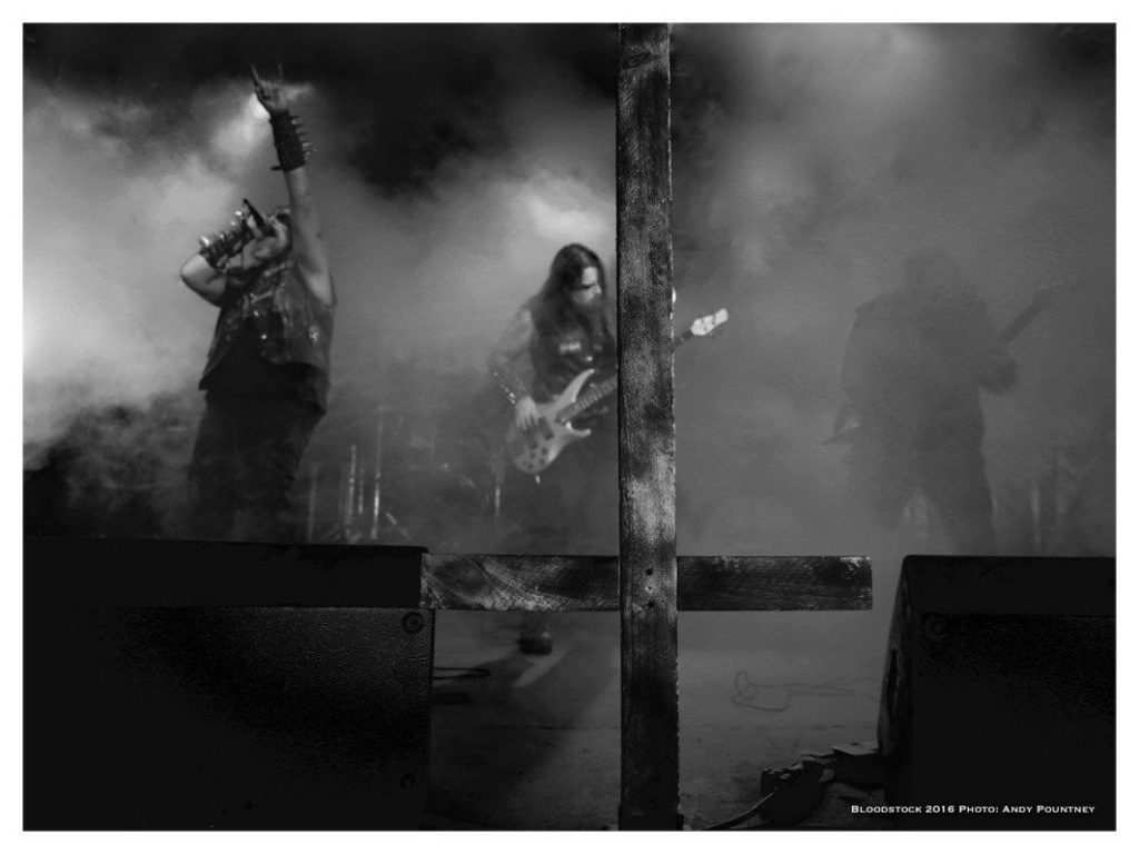 heathen deity live on stage with an inverted wooden cross