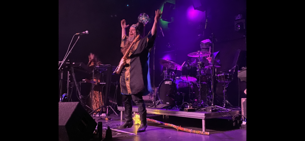 HENGE vocalist raises both hands to the crowd in celebration between guitar strums