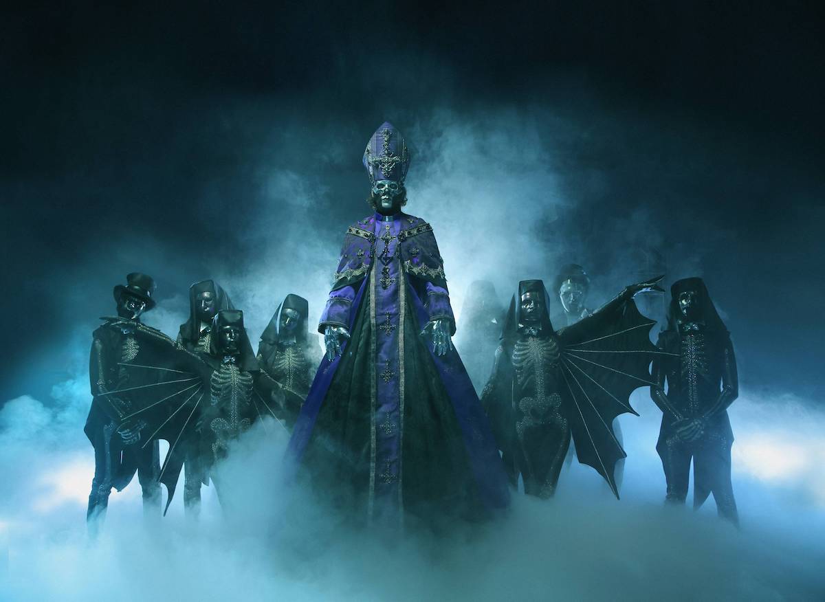 New Ghost Single - Papa V Perpetua in full papal robes, with four nameless ghouls stood each side, in a dark space with turquoise smoke surrounding the group.